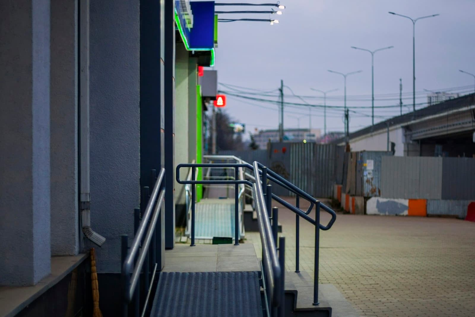 A ramp with handrails running beside steps up to a shop entrance
