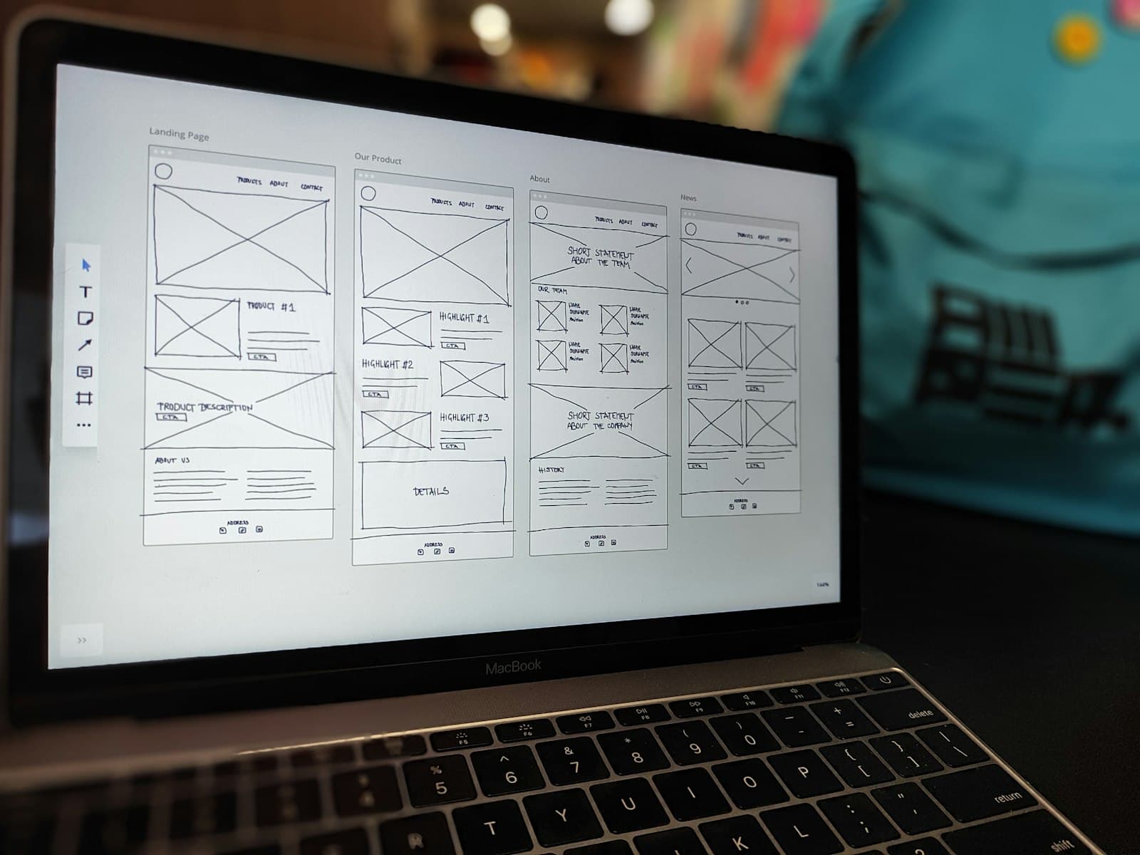 A laptop on a table showing wireframe sketches of page layouts